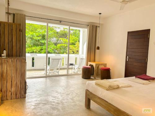 希克杜沃Jippie The Villa的一间卧室，里面有一张床和一扇大窗户。