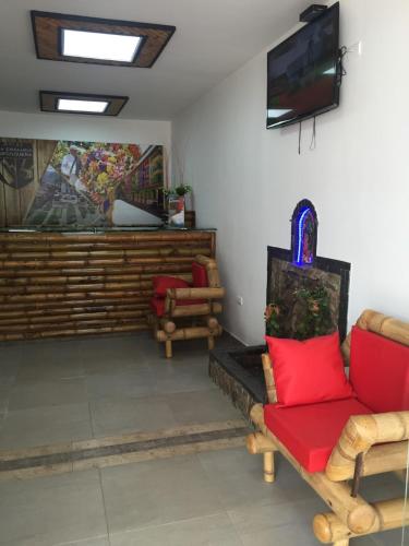 a living room with a red couch and a tv at Hotel la Embajada Antioqueña in Cúcuta