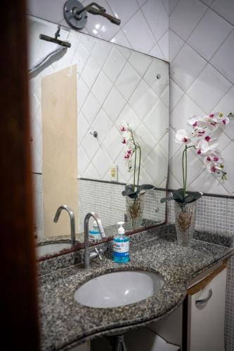 a bathroom sink with two vases with flowers in it at O Plácido Arte Hostel in Belém
