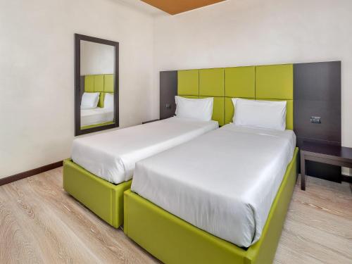 two beds in a hotel room with a mirror at Park Hotel Cassano in Cassano dʼAdda