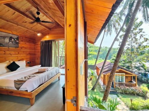 a bedroom with a bed and a large window at Tranquill riverview resort by trideus-Saipem, Candolim in Candolim