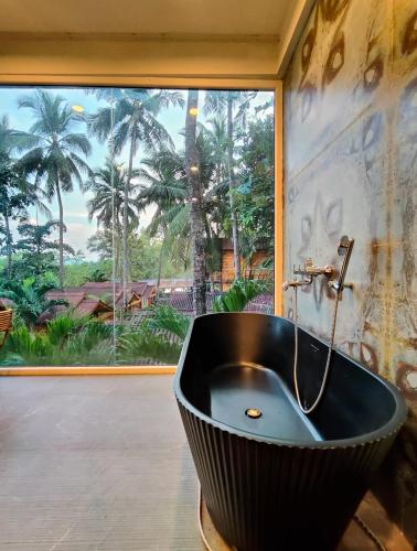 a black bath tub in a room with a window at Trideus Tranquil riverside resort -Saipem, Candolim in Candolim