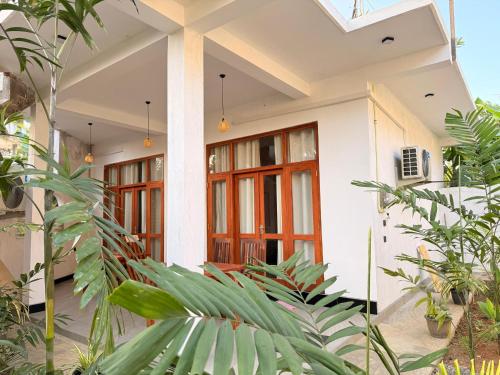 ein weißes Haus mit roten Türen und einigen Pflanzen in der Unterkunft Pabalu House in Ahangama