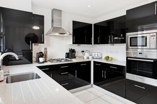 a black and white kitchen with a sink and a microwave at Stylish 3-Bed House in Newton-le-Willows - Private Parking & Garden in Newton-le-Willows