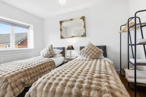 a bedroom with two beds and a mirror at Stylish 3-Bed House in Newton-le-Willows - Private Parking & Garden in Newton-le-Willows