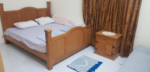 a bedroom with a wooden bed and a night stand at Men-only house in Khor Fakkan in Khor Fakkan