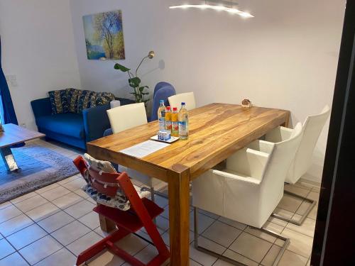 韦尔策Gemütliche 2 Zimmer Ferienwohnung mit Terrasse Fernsehsessel Spülmaschine Grill Schaukel, fußläufig zu S-Bahn nach München und See, ideal zum Entspannen aber auch zum Arbeiten的配有木桌和白色椅子的餐厅