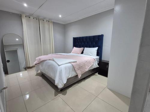 un dormitorio con una cama con cabecero azul en Maglovir Economy, en Tiervlei