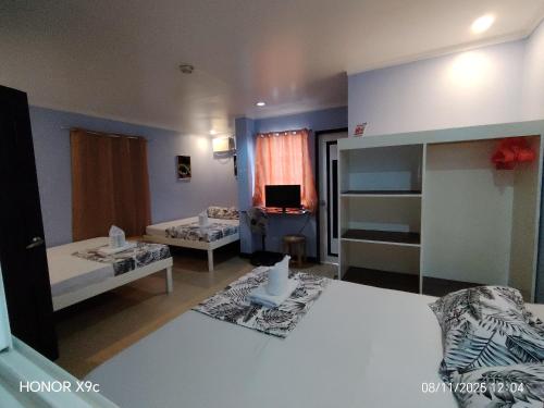 Habitación grande con 2 camas y TV. en Joaquinn's Bed and Breakfast, en El Nido