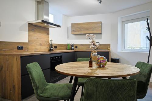 eine Küche mit einem Holztisch und grünen Stühlen in der Unterkunft La charmante maison Cosy à Saint-Avold in Saint-Avold