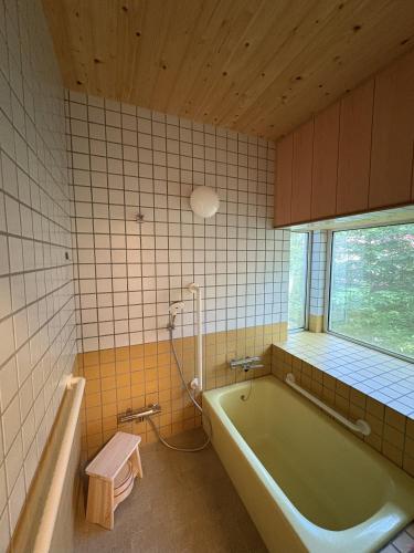 a bathroom with a bath tub and a window at Mountain chalet getaway at Fuji-Sanroku 富士山麓のシャレー風山荘 in Narusawa