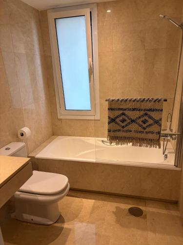 a bathroom with a toilet and a tub with a window at Los Granados Stunning 2 Bed Beach Apartment in San Luis de Sabinillas