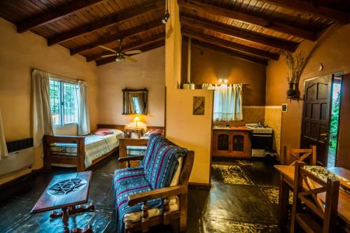 una sala de estar con un sofá y una cama en una habitación en Cabañas Atardeceres, en Capilla del Monte