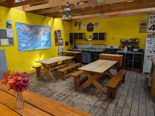 a restaurant with wooden tables and a yellow wall at Sven's Basecamp Hostel in Fairbanks
