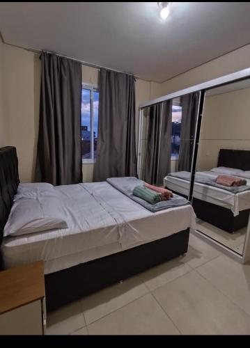 a bedroom with two beds and a large window at Apto ALTO PADRÃO com Churrasqueira, Cama Ortopedica e ar Condicionado 300m da praia acomoda 06 PESSOAS in Piçarras