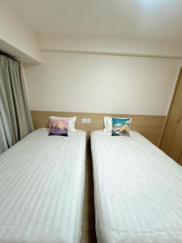 twee bedden naast elkaar in een kamer bij katsu house 心斋桥 in Osaka