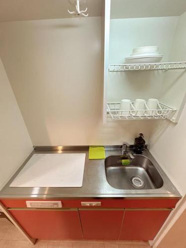 een keuken met een wastafel en een plank met borden bij katsu house 心斋桥 in Osaka