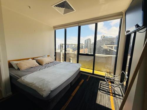 Central Melbourne 2BR Balcony Apartment في ملبورن: سرير في غرفة ذات نافذة كبيرة