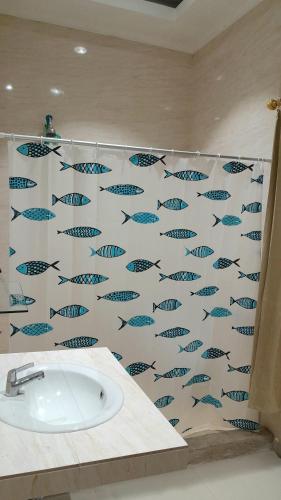 a bathroom with a fish pattern on the wall at Yulides home gardens in Cindakir