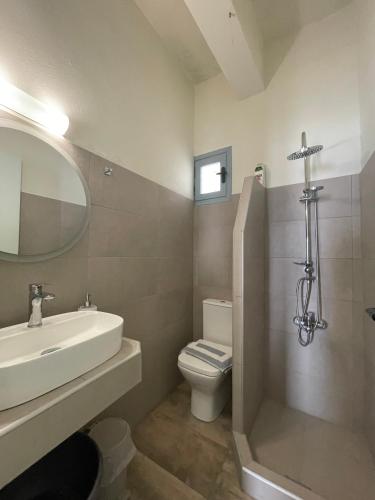 a bathroom with a sink and a toilet and a mirror at Giant Woman in Tsoutsouros