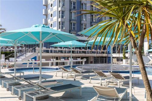 索托马里纳B&B Hotel Chioggia Airone的泳池旁边的一组椅子和遮阳伞