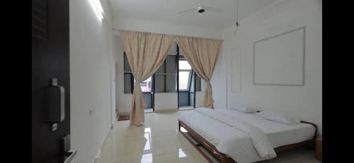 a white bedroom with a bed and a window at AZURE stay happy in Pudunagaram