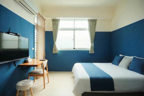 ein blaues Schlafzimmer mit einem Bett und einem Fernseher in der Unterkunft Miruku Homestay in Taitung