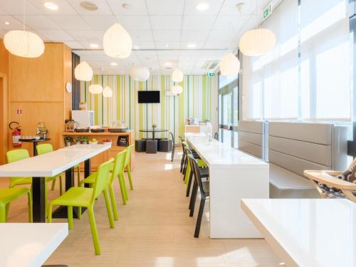 un ristorante con tavoli bianchi e sedie verdi di B&B Hotel Ravenna a Ravenna