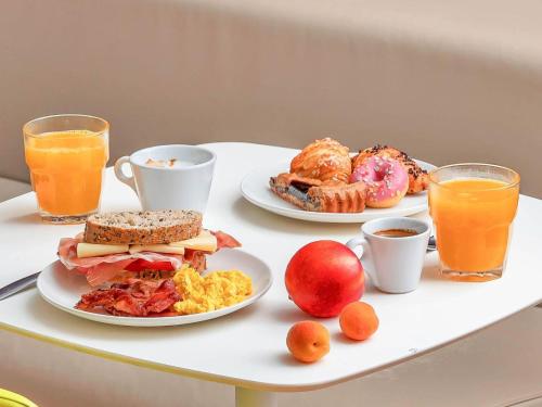 een tafel met twee borden ontbijtproducten en jus d'orange bij B&B Hotel Milano Sant'Ambrogio in Milaan