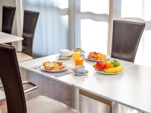 un tavolo con due piatti di cibo per la colazione e succo d'arancia di B&B HOTEL Settimo Torinese a Settimo Torinese
