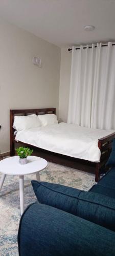 Cette chambre comprend deux lits, une table et un canapé. dans l'établissement BlueByMis, à Muchatha