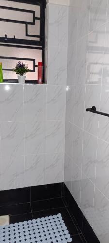 La salle de bains est pourvue d'une douche et de carrelage noir et blanc. dans l'établissement BlueByMis, à Muchatha