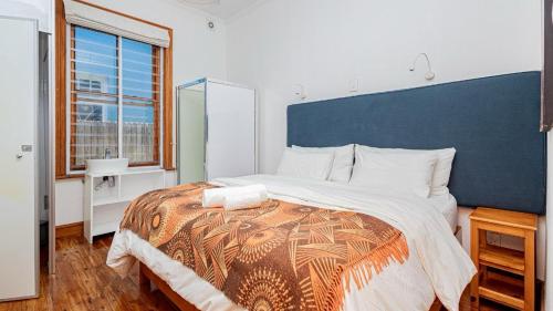 a bedroom with a large bed with a blue headboard at Blossom Boutique Guesthouse in Muizenberg
