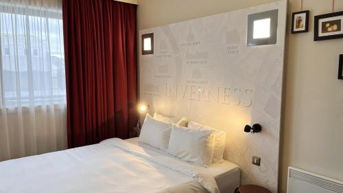 Una habitación de hotel con una cama y un cartel en la pared. en B&B HOTEL Inverness, en Inverness