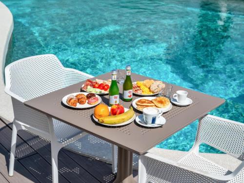 een tafel met borden eten en drinken naast een zwembad bij B&B Hotels Park Hotel Suisse Santa Margherita Ligure in Santa Margherita Ligure