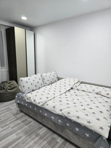 a bed in a room with a white wall at Studio modern 10 min de centru, perfect pentru doi in Chişinău