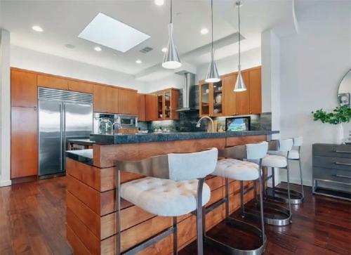 una cocina con barra con taburetes blancos en Elegant Three-Bedroom Beachfront Home With Wide Ocean Views, en Redondo Beach