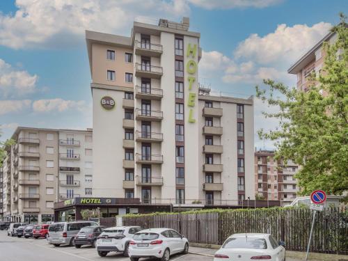 ein großes weißes Gebäude mit auf einem Parkplatz geparkten Autos in der Unterkunft B&B Hotel Firenze Novoli in Florenz