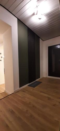 una stanza vuota con una grande parete nera e pavimenti in legno di Primslodge a Nalbach