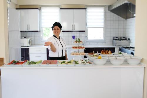 a woman standing in a kitchen preparing food at Fethiye Pension in Fethiye