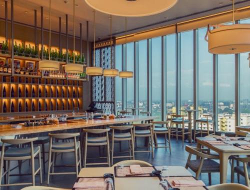 ein Restaurant mit Tischen und Stühlen und großen Fenstern in der Unterkunft Seaview stay at Cinnamon Life Residence - City of Dreams in Colombo