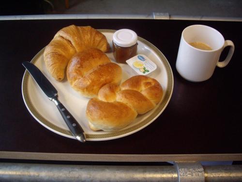 Un plato de croissants sobre una mesa con una taza de café. en Depot 195 - Hostel Winterthur, en Winterthur
