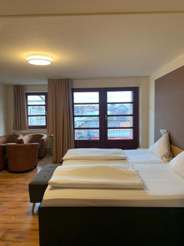 een slaapkamer met twee bedden en een bank en ramen bij Hotel an der Hörn in Kiel