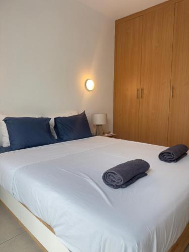 a bedroom with a large white bed with blue pillows on it at A Home at Coralli - Protaras Beach Apartment, 30 m from beach in Protaras