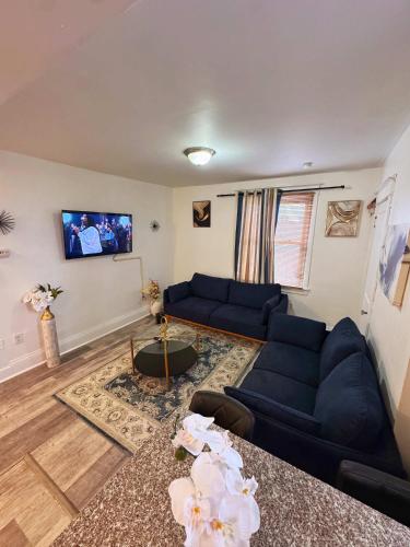 un soggiorno con divani blu e TV a schermo piatto di Natvy Alpha Suite - 3 Bedroom a Munhall