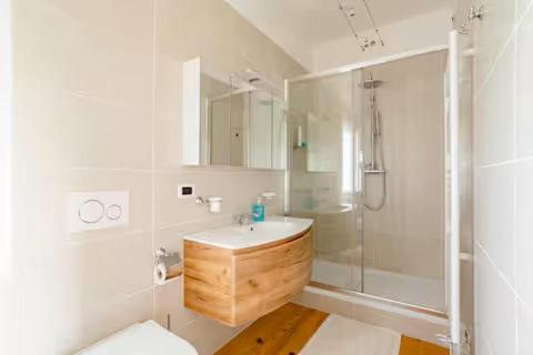 a white bathroom with a sink and a shower at La casa nel verde in Montereale Valcellina