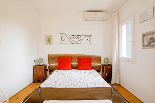 a bedroom with a bed with two red pillows at La casa nel verde in Montereale Valcellina