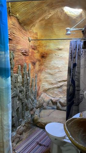 a bathroom with a wooden wall with a toilet at Cahuita Vibe in Cahuita