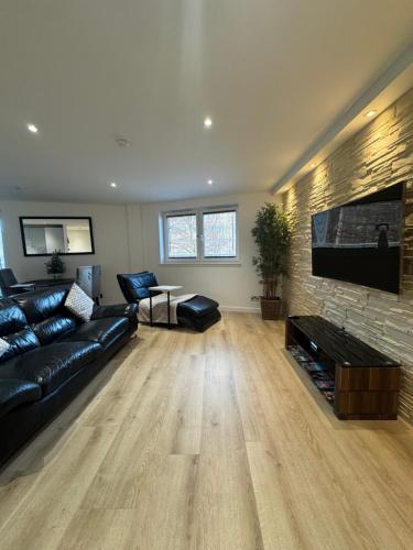 a living room with a black leather couch and a flat screen tv at KM Granton Apartment in Edinburgh