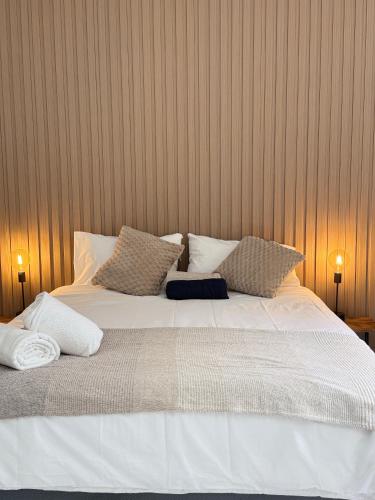 a large bed with white sheets and pillows at Tambo Touchdown Suites in Benoni